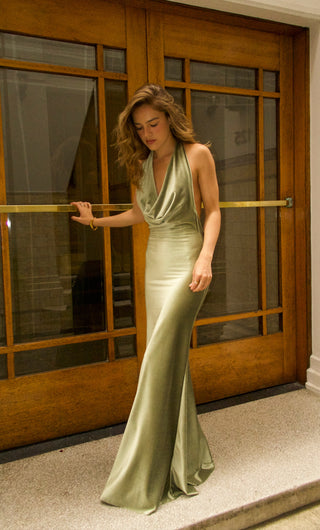Woman in a green evening gown standing in front of a wooden door.